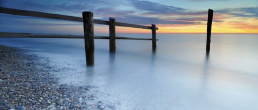 Sunset at Darßer Ort, fence and posts on the Baltic Sea as the border of the cordoned-off core zone