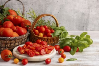 Sliced tomatoes on a white marble slab, surrounded by fresh tomatoes in baskets and herbs