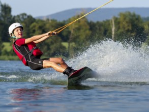 Boy or girl, water sports and fast ride with wakeboard, red life jacket, water skiing in the wake