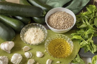 Courgettes, sunflower seeds, cheese, olive oil, garlic and basil on a table