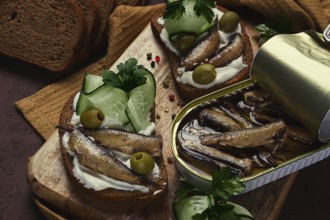 Sandwiches, black bread with sprats, cream cheese, cucumbers, on a cutting board, top view,