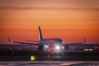 Early in the morning in front of sunrise at the airport, a Lufthansa aircraft stands ready for