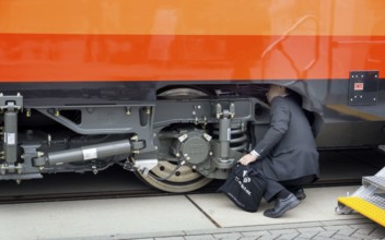 Chinese visitors to the InnoTrans trade fair in Berlin take a look at the undercarriage under a