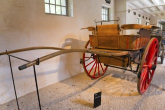 Historic wooden carriage with red wheels in a museum exhibition room, Tonneau carriage of the