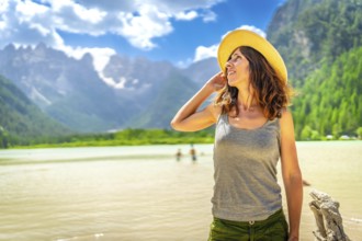 Tourist wearing a straw hat enjoying the stunning view of the dolomites reflected in the serene