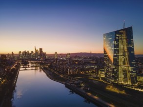 The lights in the offices of the European Central Bank (ECB) and the Frankfurt skyline glow in the