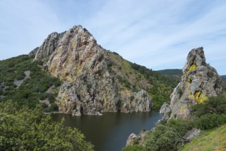 Large rock formations on the banks of a river under a blue sky, Salto del Gitano, River Tagus,