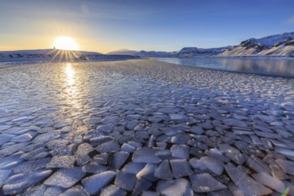 Ice floes on a lake in front of snowy mountains, sunset, backlight, snow, winter, Snaefellsnes,