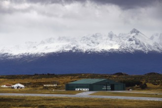 View from the deck of the cruise ship to an industrial hall in front of a snow-covered mountain