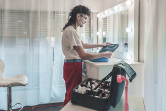 Professional makeup artist unpacking cosmetics bag in brightly lit dressing room, preparing for