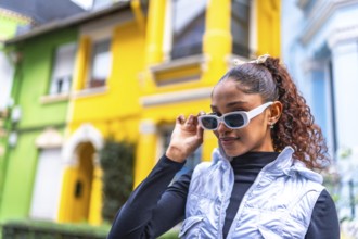 African american woman wearing modern futuristic clothes and sunglasses standing in a colorful