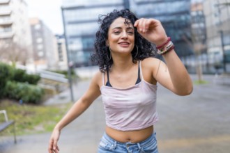 Carefree young latin woman enjoying dancing outdoors in urban environment, expressing joy and