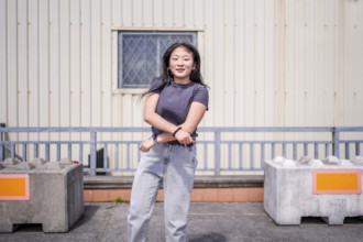Happy vital young asian woman gesturing while dancing k-pop choreography in the city