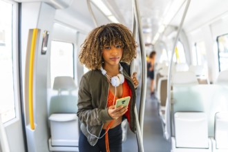 Portrait of a beauty latin young woman standing on the metro while using phone