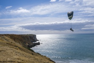 Sagres, Algarve, Portugal - Paraglider flying on the town beach Praia da Mareta, at the back left