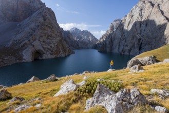 Tourist at the blue mountain lake between rocky steep mountain peaks, Kol Suu Lake, Sary Beles