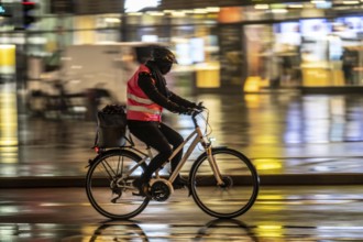 Street at the central station, cyclist, rainy weather, city centre, in the evening, Essen, North