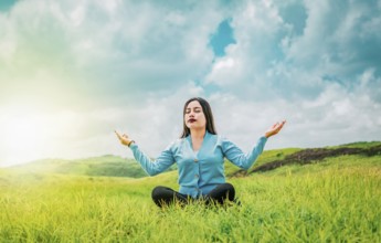 Beautiful girl meditating on the grass in a beautiful field. Portrait of relaxed young woman doing