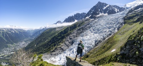Mountaineer standing on a rock, mountain landscape with glacier Glacier des Bossons and summit of