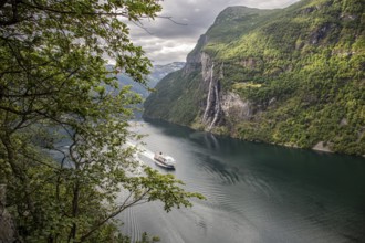 A cruise ship sails through the Gairanger Fjord surrounded by steep mountains and the Seven Sisters