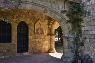 Monastery of Our Lady of Mount Filerimos, A stone archway of a medieval church with a dark door,