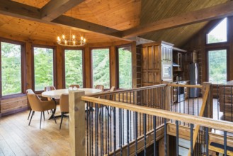 Staircase, round wooden dining table with tan leather armchairs in dining room, plus kitchen inside