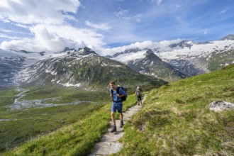 Two mountaineers on hiking trail in picturesque mountain landscape, mountain peak with snow and