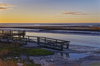 Evening landscape on the Wadden Sea. A footbridge leads over the mudflats. UNESCO World Heritage