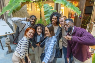Group of diverse coworkers gesturing and smiling while taking selfie together