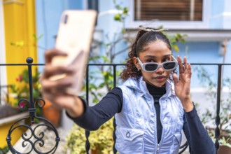 Beauty african american woman millennial in urban clothes taking selfie outside a colorful house