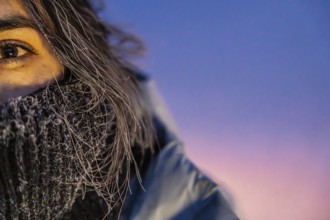 A woman with long hair is wearing a scarf and a scarf is covering her face