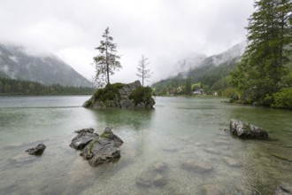 Hintersee near Ramsau, surrounded by forests and mountains under a cloudy rainy sky, fog,