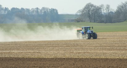 Spring farming, spreading fertilizer with tractor on field in Ystad municipality, Skåne county,