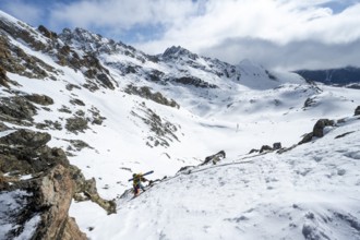 Mountaineer with skis climbing up a steep snow slope to the fork Porta d'Es-cha, ski tour Bündner