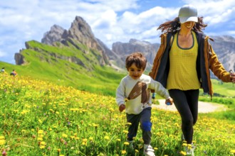 Tourists enjoying summer vacations in the italian alps, running through a field of wildflowers with