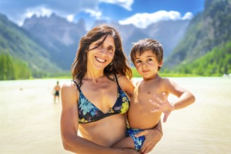 Mother holding her son while enjoying a swim in the beautiful lago di landro in the italian