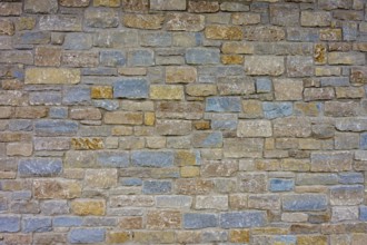 Wall of colourful natural stones in shades of blue and beige with uneven texture, Würzburg,