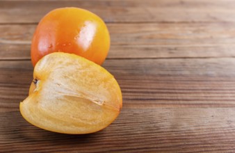 Ripe orange persimmon on brown wooden background, with copy space
