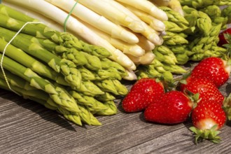 Green asparagus, white asparagus and fresh strawberries decorated on a rustic wooden table