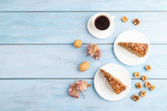 Walnut and hazelnut cake with caramel cream, cup of coffee on blue wooden background. top view,