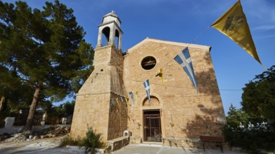 Church entrance with bell tower and Greek flags under a bright blue sky, Koroni, Byzantine