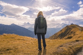 A person looks into the distance, surrounded by mountains under a dramatically cloudy sky,