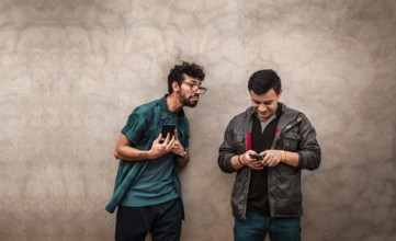 Young man spying on his friend's cell phone. Young man spying friend using phone