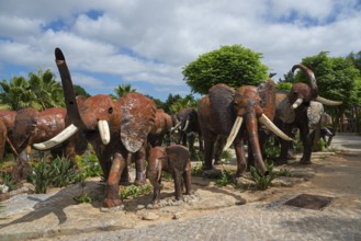 Herd of metal sculptures depicting elephants in a park with trees under a cloudy sky, Bacalhôa,