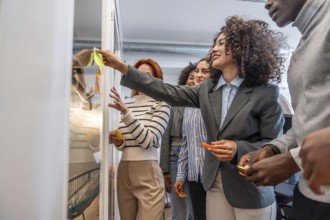 Hispanic beauty woman using adhesive note on glass during creative process in a modern coworking
