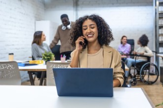 Cheerful woman talking to the mobile phone while working in a coworking space