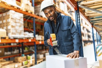 African man closing boxes of merchandise using a tape gun at a distribution warehouse