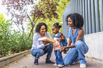 Mother and grandmother showing a game to a girl outdoors when they picking up from school