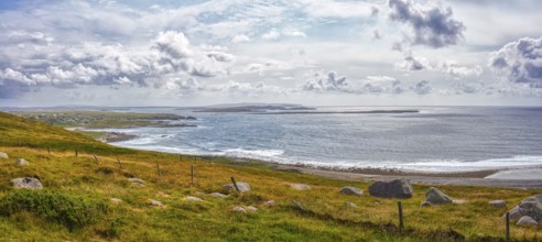 Panoramic view of a picturesque coastal landscape with cliffs, green grass and calm sea under a