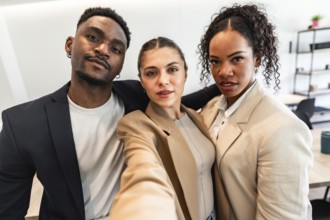 Three diverse business professionals are taking a selfie, showcasing their teamwork and positive